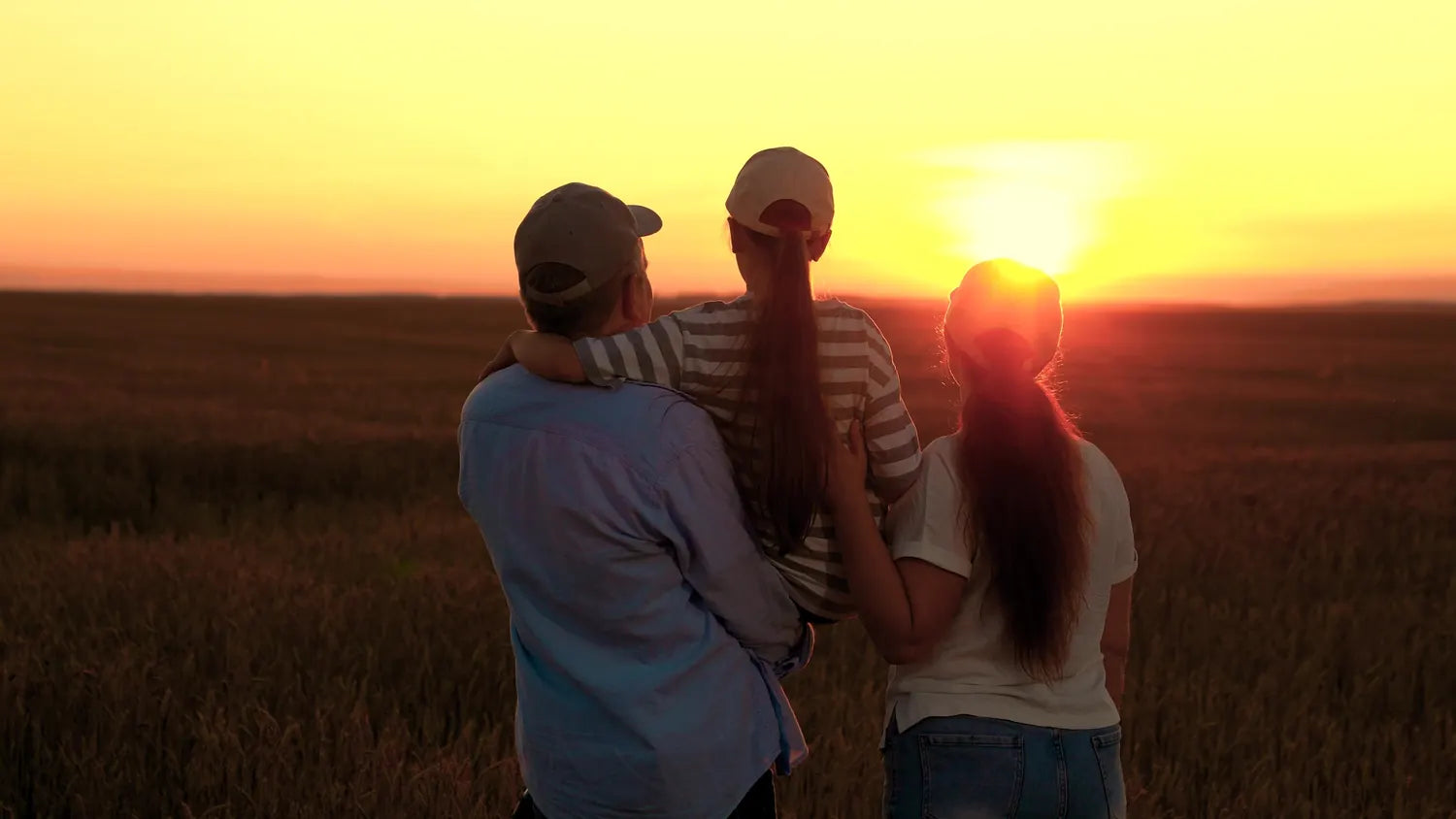 A Canadian family embracing in a prairie field at golden hour