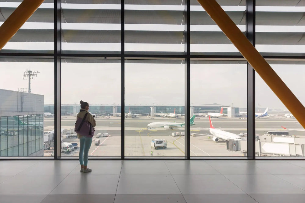 A traveller at a large airport window watching the aircraft