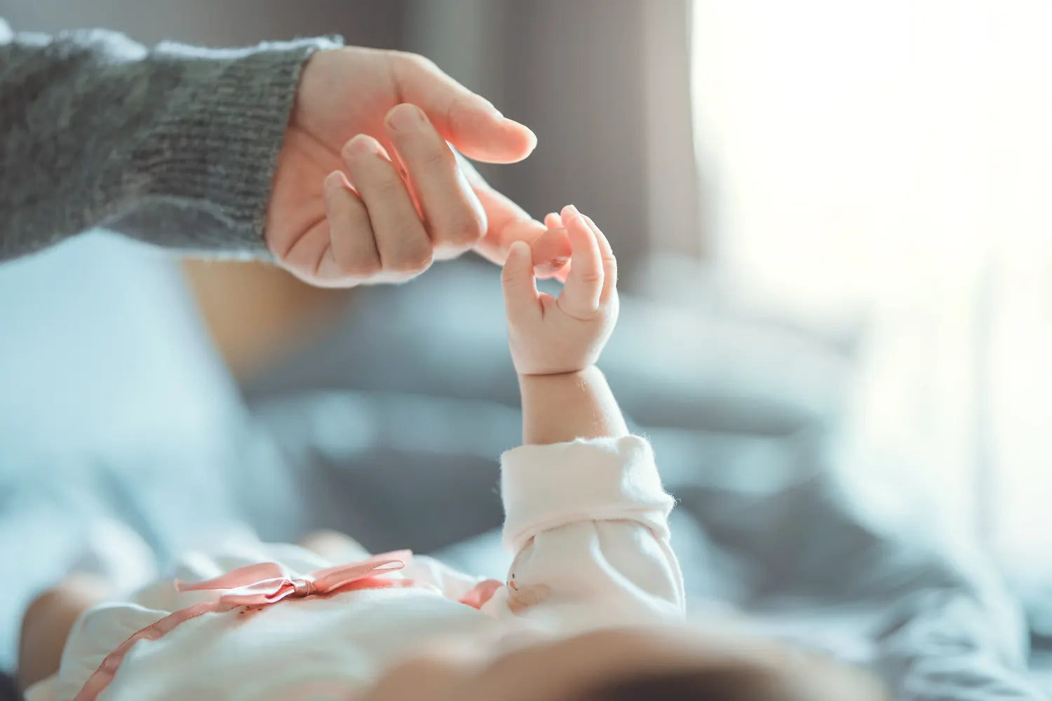 A newborn holding a parent's finger